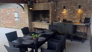 An outdoor patio with a brick wall, a stone fireplace, and a dining table with chairs. - Villa Sorella Beautiful 3-bedroom Villa in Karanac (Knezevi Vinogradi)