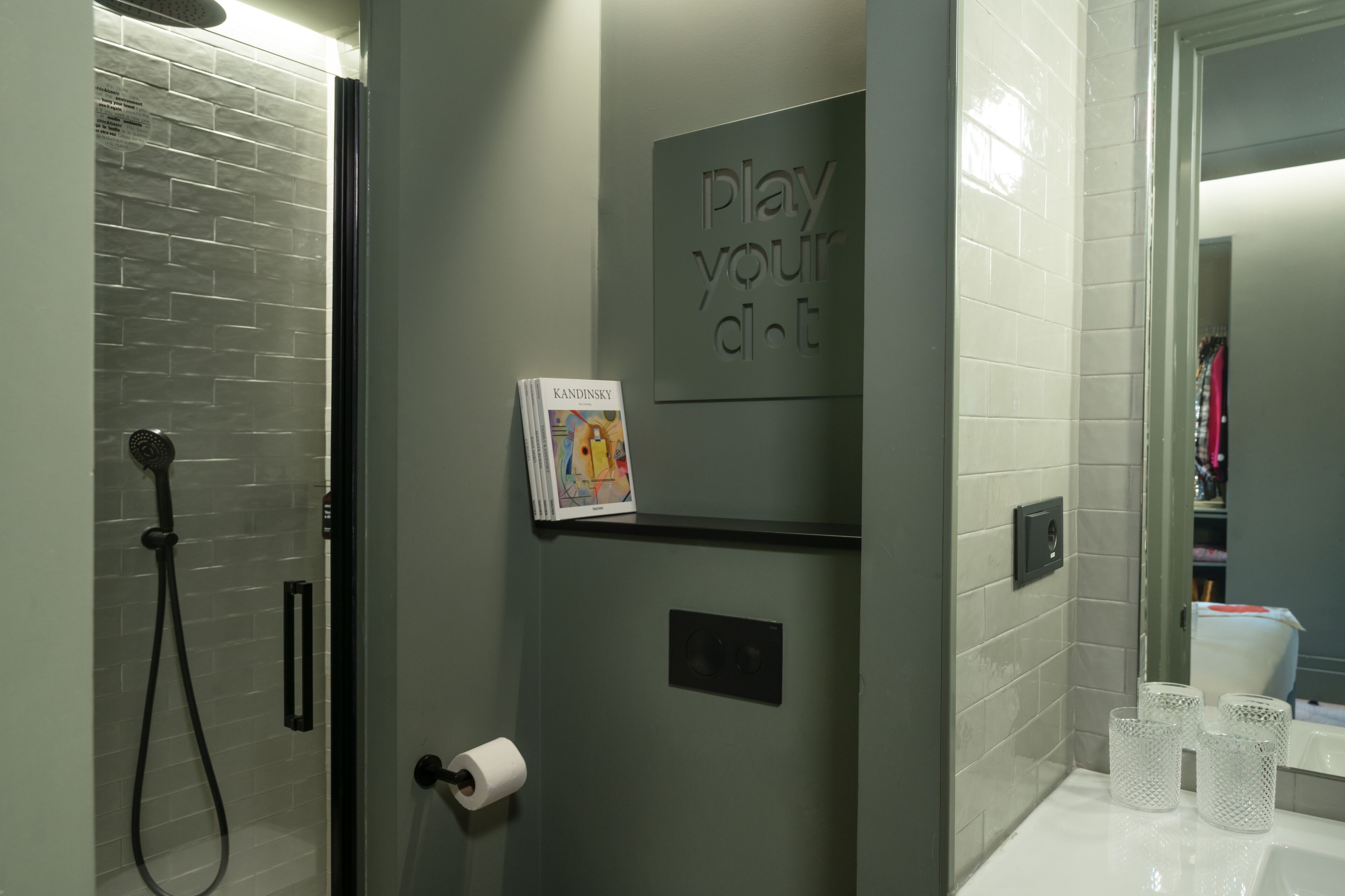 A bathroom with a shower, toilet paper, a magazine rack, and a mirror.