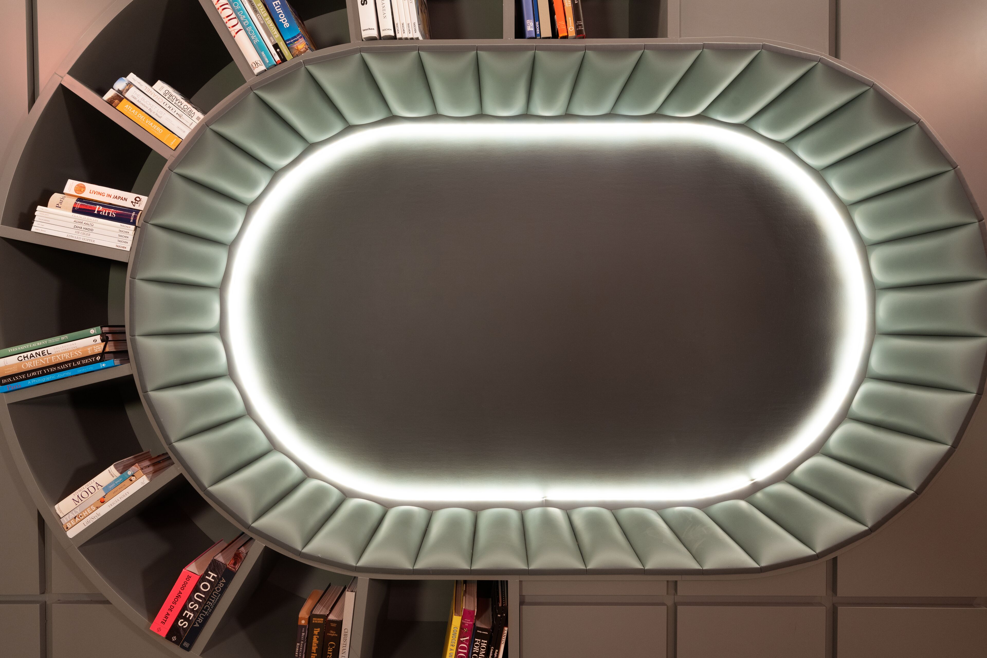 Una estantería moderna y circular con una zona central iluminada, rodeada de libros.
