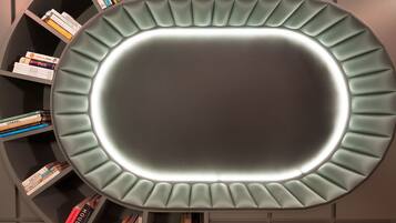 Una estantería moderna y circular con una zona central iluminada, rodeada de libros.