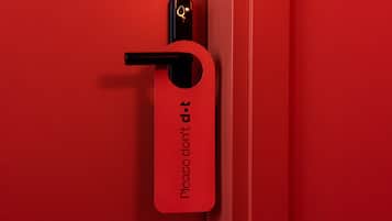 Una puerta roja con un picaporte negro y una etiqueta roja que dice 'Por favor, no molestar'.