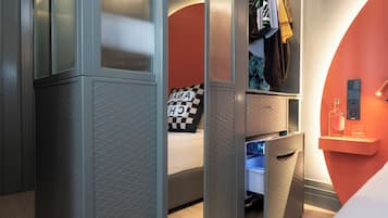 Une chambre à coucher moderne avec un lit, une armoire et une table de chevet sur laquelle se trouvent une bouteille et des verres.