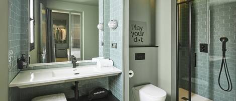 A modern bathroom with a white sink, mirror, and glass shower enclosure.