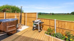 A wooden deck with a hot tub, a grill, and a wooden fence. - Outbak Shepherds Hut - sleeps 2 guests in 1 bedroom (Hailes)