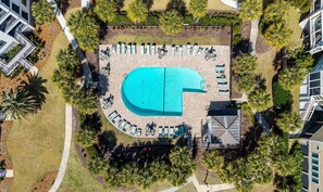 An aerial view of a resort with a large pool, lounge chairs, and palm trees. - Summer House 202 by Deserving Vacations (Isle of Palms)