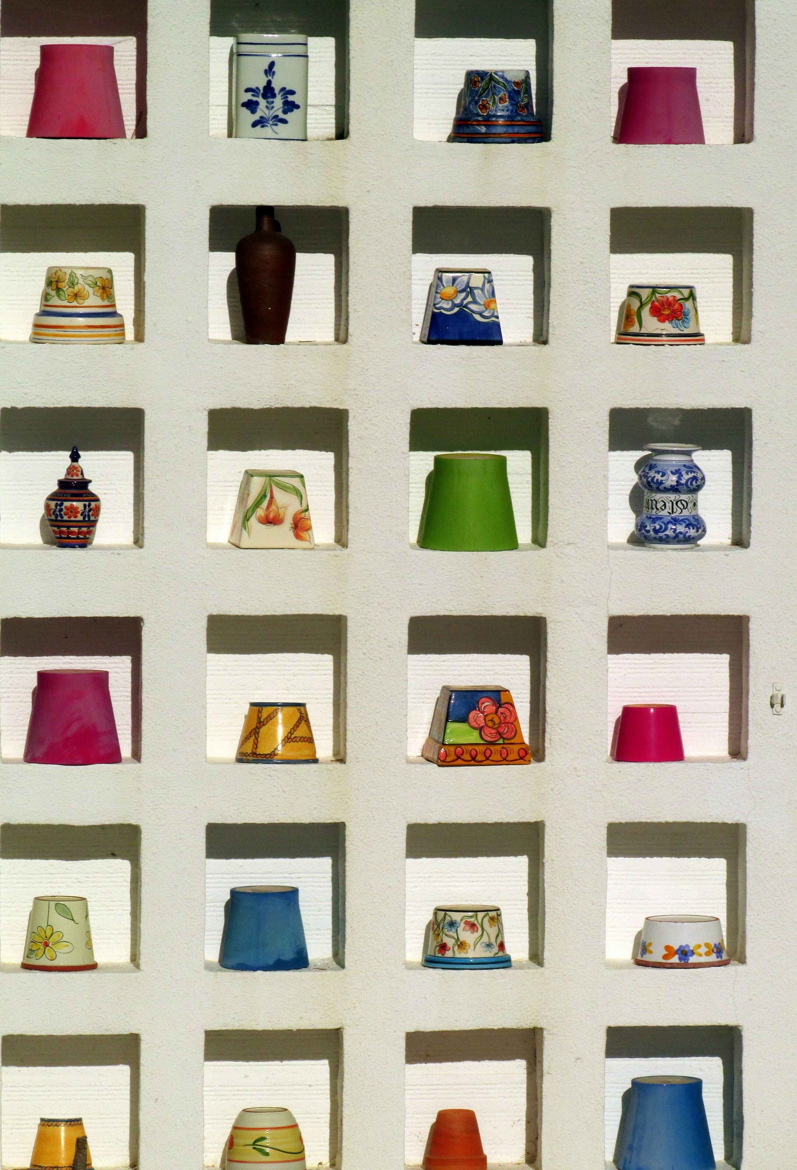 A wall with multiple square frames, each containing a different ceramic object.