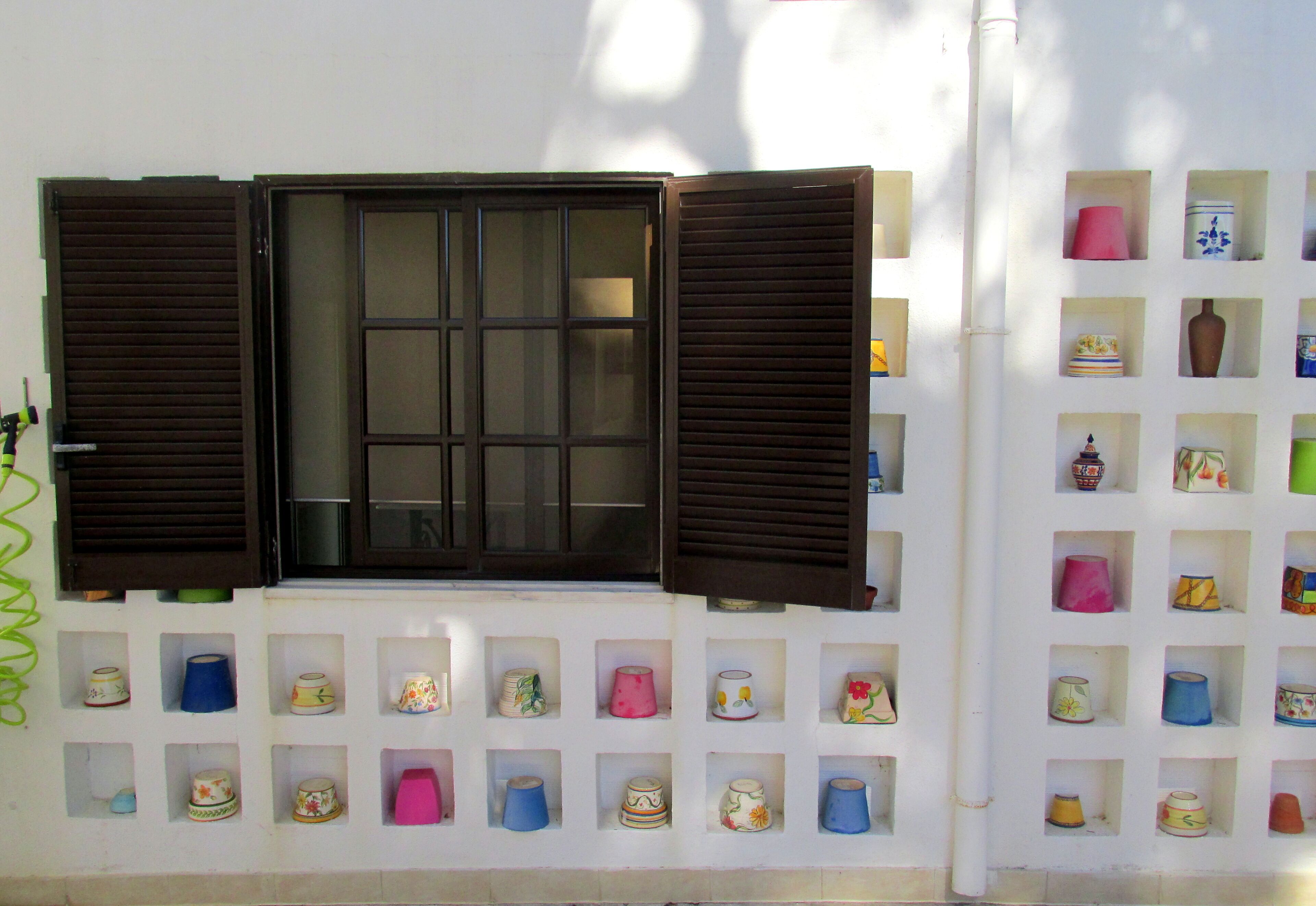 A wall with a window and multiple shelves of decorative items.
