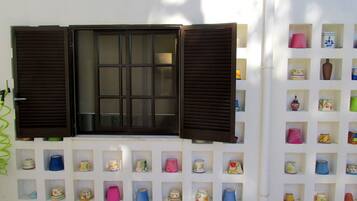 A wall with a window and multiple shelves of decorative items.