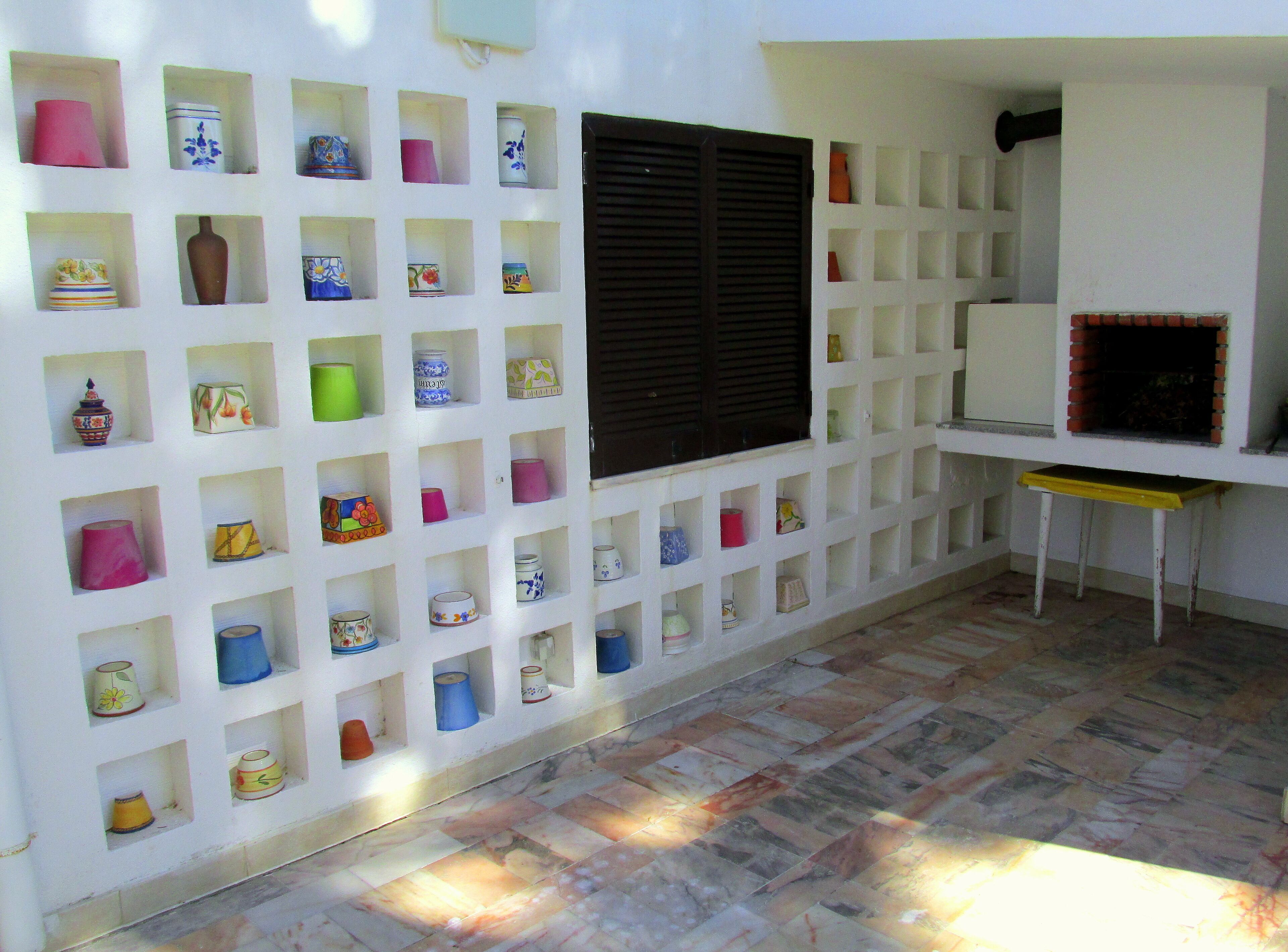 A room with a white wall displaying various ceramic containers in a grid pattern.