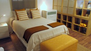 Une chambre bien rangée, avec un lit, des tables de chevet, une armoire en bois et une petite chaise.