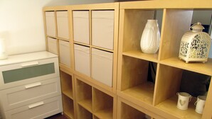 Une pièce avec un meuble en bois doté de plusieurs compartiments, un bureau blanc avec des tiroirs et un plancher en bois.