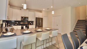 A modern kitchen with white cabinets, stainless steel appliances, and a central island with bar stools.