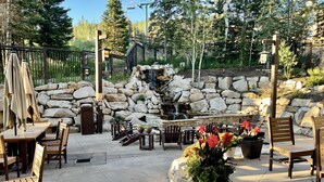 An outdoor patio area with stone walls, wooden furniture, and a waterfall feature.