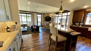 A spacious kitchen with wooden flooring, a dining area with a large table and chairs, and a bar area with a countertop and seating.