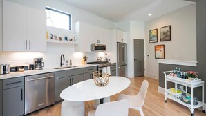 Una cocina moderna con electrodomésticos de acero inoxidable, una mesa de comedor blanca y una silla blanca.