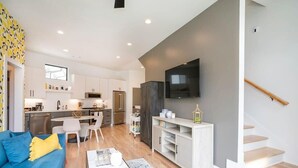 Un apartamento moderno con sala de estar, comedor, cocina y una escalera.