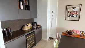 Moderni keittiö, jossa on tummat kaapit, sisäänrakennettu uuni sekä ruokailutila pöytineen ja tuoleineen.