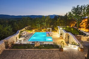 A swimming pool with lounge chairs and a stone wall surrounding it, set against a mountainous backdrop. - Villa with stunning underwater view, fenced private park (Imotski)
