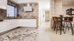 A modern kitchen with white cabinets, a marble backsplash, and a dining area with a table and chairs. - Villa with stunning underwater view, fenced private park (Imotski)