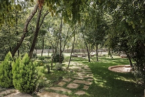 A garden with stone pathways, trees, and a circular seating area.