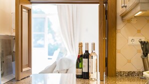 A kitchen with a granite countertop, wine bottles, and a wooden cabinet. - Semi-detached house, 500m from the lake in Quinta do Lago, perfect for your vacation (Almancil)