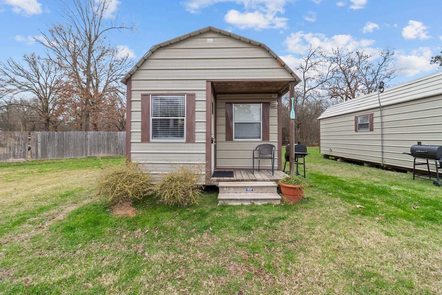 A small single-story house with a front porch, a mailbox, and a grill in the yard.