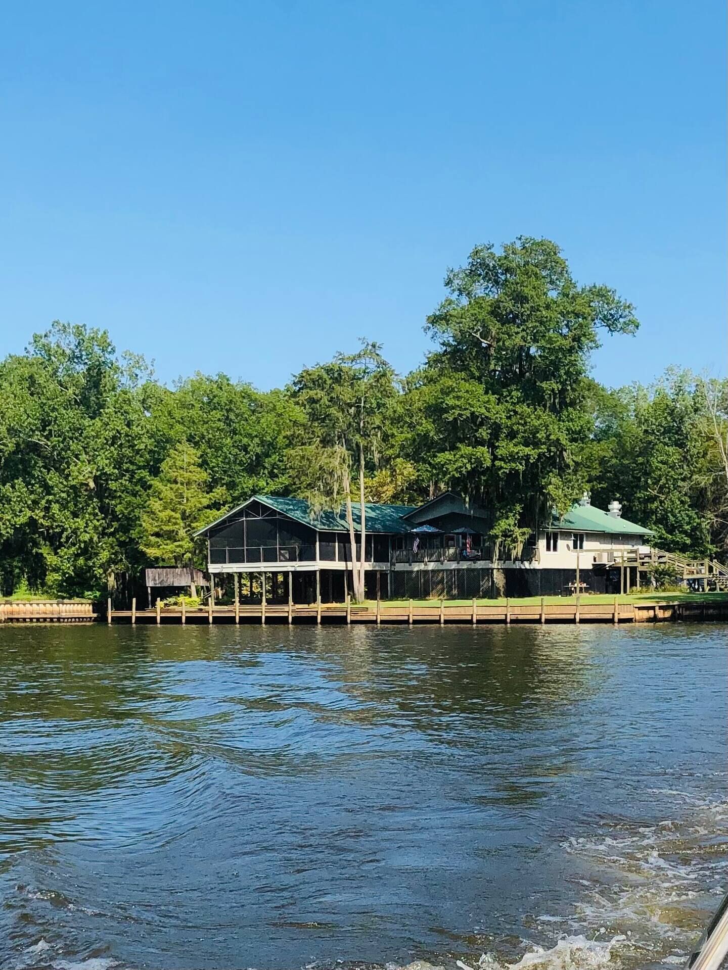 A waterfront property with a dock extending into the water, surrounded by lush greenery.