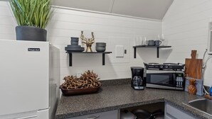 Et moderne køkken med hvide skabe, en granitbordplade, kaffemaskine, mikroovn og en dekorativ dåhjort.
