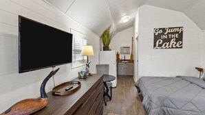 Et kompakt værelse med seng, skrivebord med fjernsyn, lille bord og tekøkken.