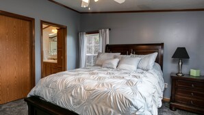Un dormitorio con cama, armario de madera y mesita de noche con lámpara.