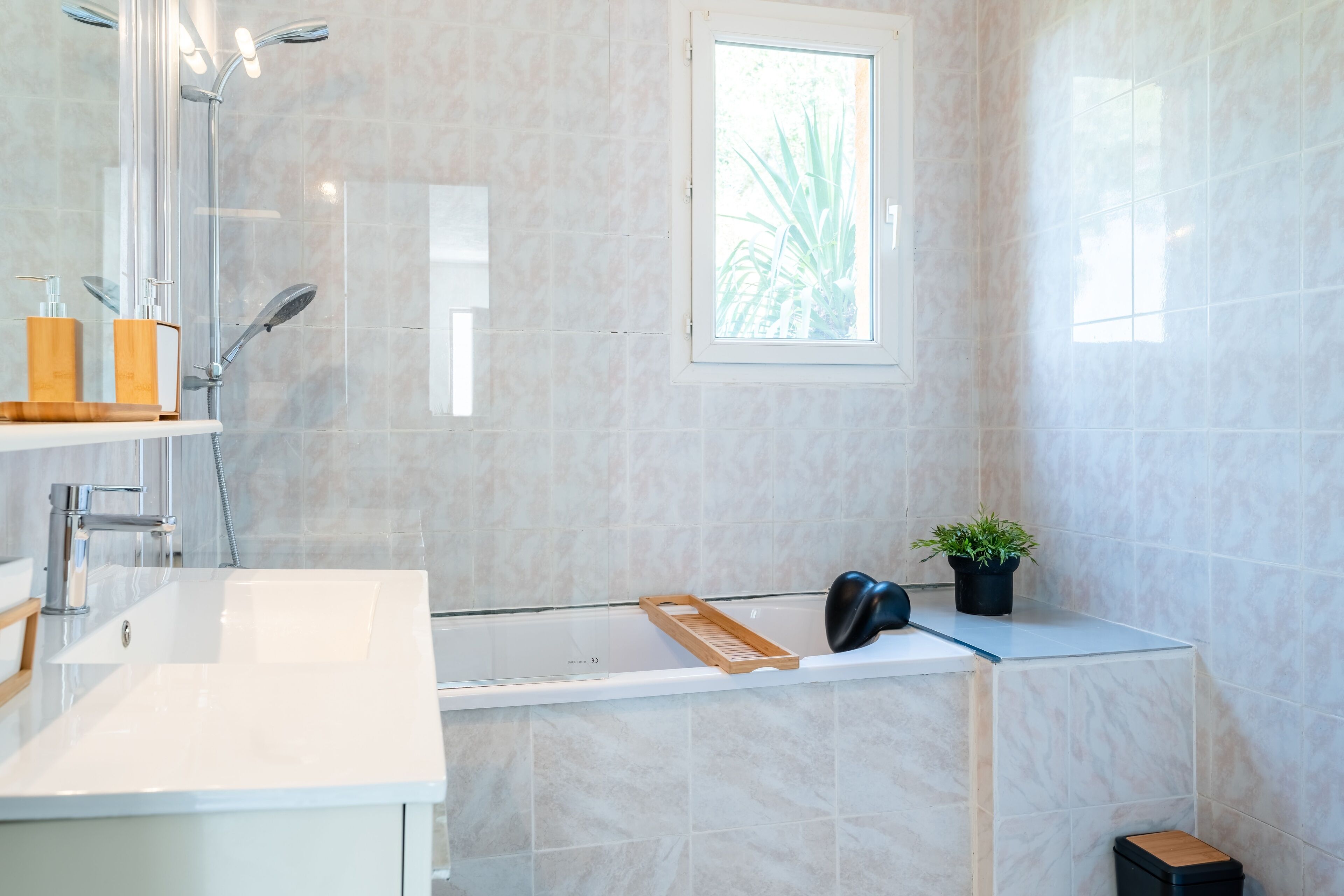 A modern bathroom with a shower, a sink, and a window.