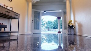 A spacious lobby with a polished marble floor, a grand chandelier, and a view through an arched doorway to an outdoor area. - Rancho Encantado VIP (El Paso)