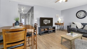 Un salon moderne comprenant un coin repas, un téléviseur, un ventilateur de plafond et une horloge murale.