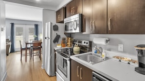 Une cuisine moderne dotée d’appareils électroménagers en acier inoxydable, de meubles en bois et d’un coin repas avec une table et des chaises.