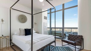 Ein Schlafzimmer mit einem Himmelbett, einer runden Wanddekoration, einem Fenster mit Ausblick und einem Ledersessel.