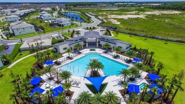 Un hotel moderno con piscina central, rodeado de palmeras y zonas de descanso.
