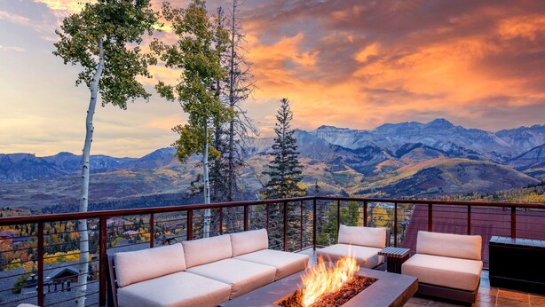 Une terrasse dotée d’un foyer extérieur, d’un espace salon extérieur et offrant une vue sur les montagnes.