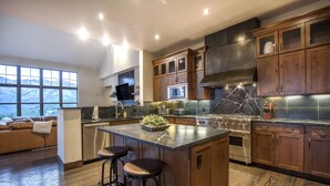 Une cuisine moderne avec des meubles en bois, un îlot central doté de tabourets, un four à micro-ondes encastré et une cuisinière.