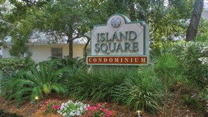 A sign for Island Square Condominium surrounded by lush greenery and flowering plants. - Beach Square – optional BIKES – Walk 2 Redfern Village, shops, and restaurants!. (St Simons Island)