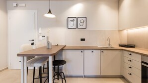 A modern kitchen with a wooden countertop, white cabinets, and a black stool. - Luxury Apartment in Plaka C (Athens)