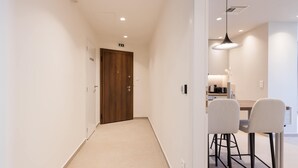 A hallway with a wooden door, a dining area with a table and chairs, and recessed lighting. - Luxury Apartment in Plaka C (Athens)
