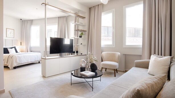 A modern living room with a sofa, a coffee table, a TV, and a bookshelf. - Luxury Apartment in Plaka C (Athens)