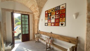 A room with a stone archway, a bench, and a wall with a colorful artwork. - Townhouse Cas Concos Santany (Cas Concos des Cavaller)