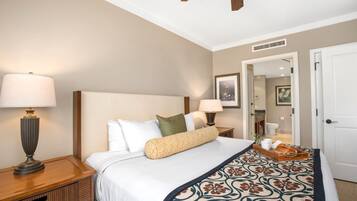 A neatly arranged hotel room with a large bed, two bedside lamps, a wooden nightstand, a tray with bread and a cup, and a door leading to a bathroom.