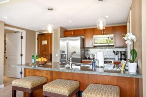 Une cuisine moderne dotée d’un îlot central, d’appareils électroménagers en acier inoxydable et de meubles de rangement en bois.