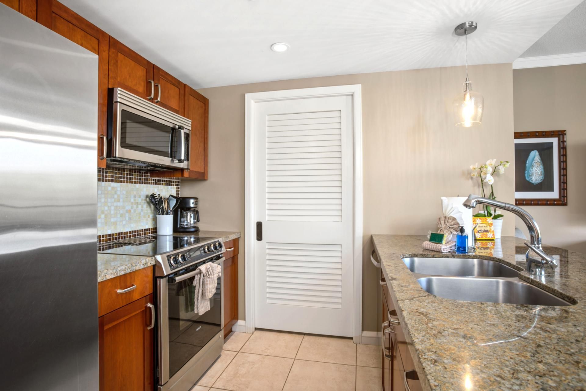 A modern kitchen with stainless steel appliances, a microwave, and a sink with a granite countertop.