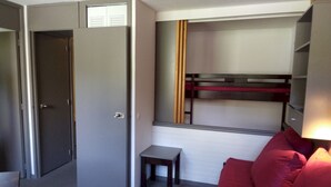 Una habitación pequeña con una litera, una mesita y un sofá.