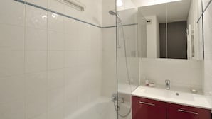 A modern bathroom with a glass shower enclosure, white tiled walls, a white sink, and a mirror. - travelski home select - Résidence Les Glaciers - Studio 3/4 personnes 318 (La Plagne)