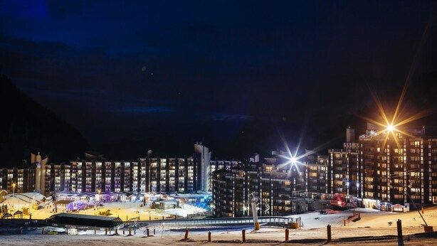 A modern hotel with multiple floors, a covered outdoor area, and a ski lift in the background. - travelski home select - Résidence Les Glaciers - Studio 3/4 personnes 318 (La Plagne)