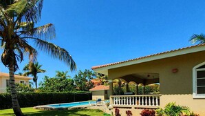 A residential property with a swimming pool, a well-maintained lawn, and a porch with a railing. - 9BD guest-friendly complex in central Sosua, 2 pools, WiFi/AC/cable TV/BBQ (Sosúa)